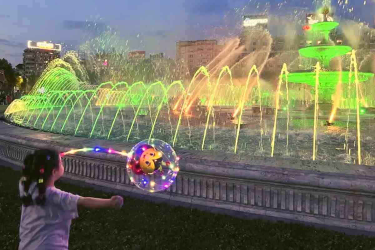 A girl plays with a balloon at a city fountain in Bucharest, Romania